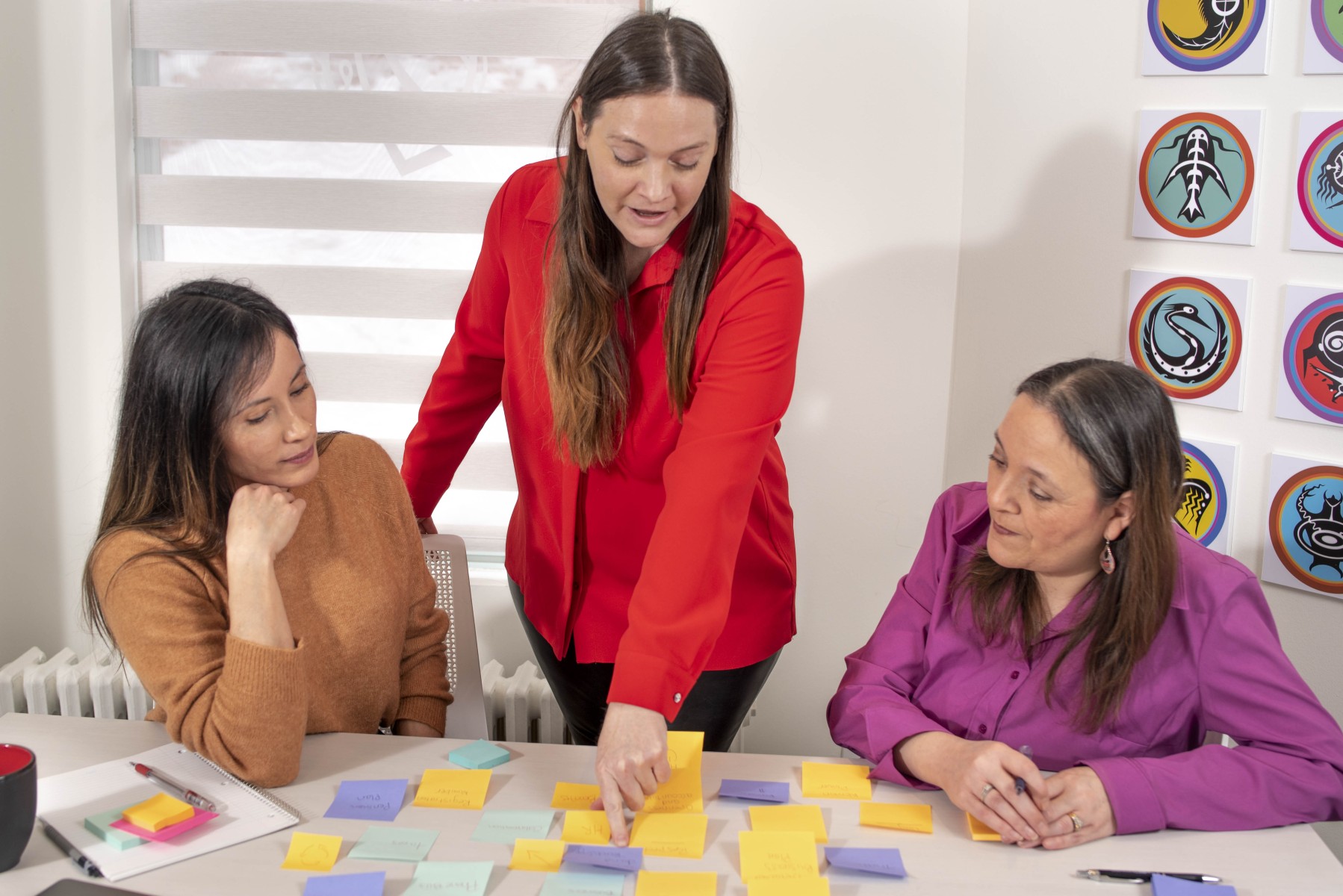 Three women plan using post-it notes in an Indigenous office space.